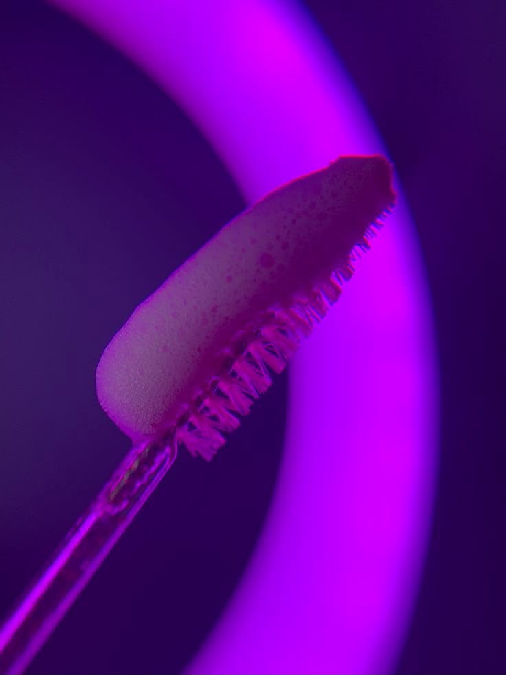 Foam on a lash wand under purple studio light